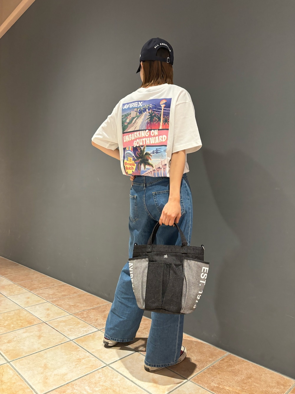 ブラック系のトートバッグ、ホワイト系のTシャツ/カットソー、ブルー系のキャップを着用したレディースの夏コーディネートの1枚目の写真