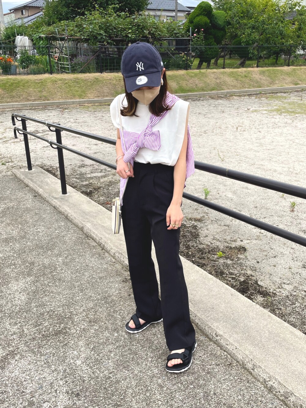 ピンク系のシャツ/ブラウス、ホワイト系のニット/セーター、ブラック系のスラックスを着用したレディースの夏コーディネートの1枚目の写真