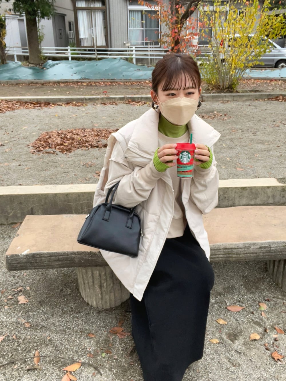 ベージュ系のスウェット、グリーン系のニット/セーター、ホワイト系のダウンベストを着用したレディースの秋コーディネートの1枚目の写真