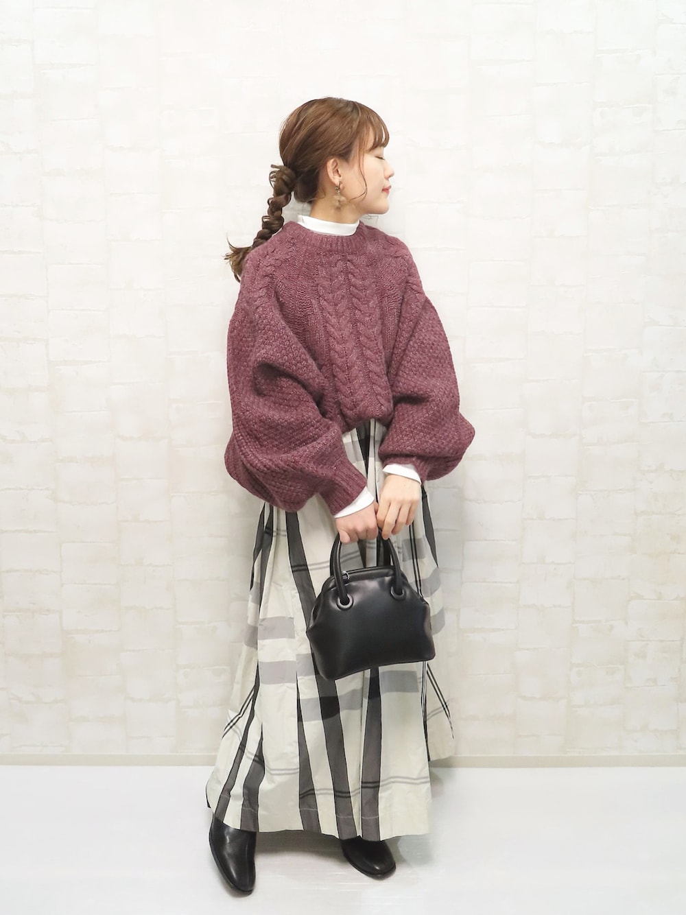 ホワイト系のスカート、パープル系のニット/セーター、ホワイト系のTシャツ/カットソーを着用したレディースの冬コーディネートの1枚目の写真