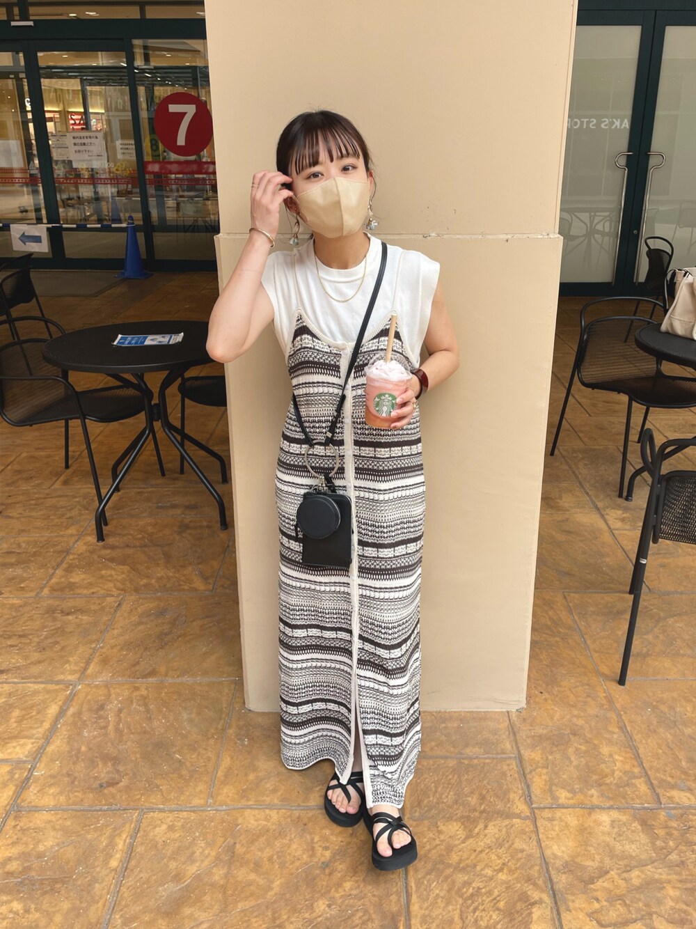 ベージュ系のワンピース、ホワイト系のニット/セーター、ブラック系のショルダーバッグを着用したレディースの夏コーディネートの1枚目の写真