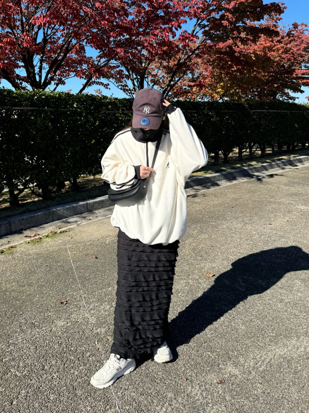 ホワイト系のスウェット、ブラック系のスカート、ホワイト系のスニーカーを着用したレディースの秋コーディネートの1枚目の写真