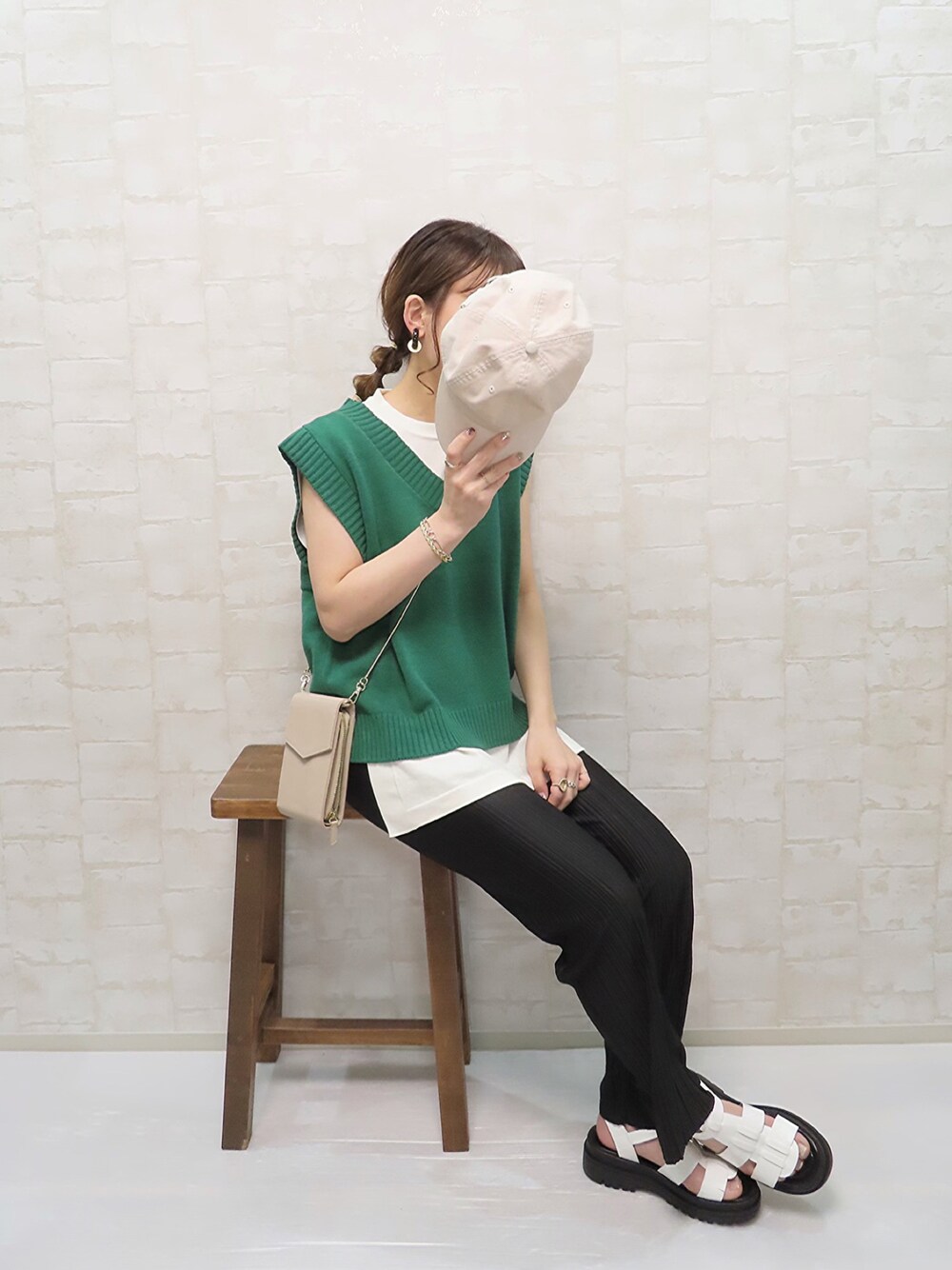 グリーン系のベスト、ホワイト系のニット/セーター、ブラック系のレギンス/スパッツを着用したレディースの春コーディネートの1枚目の写真