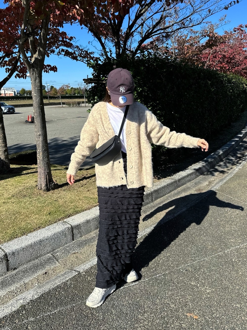 ベージュ系のカーディガン/ボレロ、ブラック系のスカート、ブラック系のショルダーバッグを着用したレディースの秋コーディネートの1枚目の写真