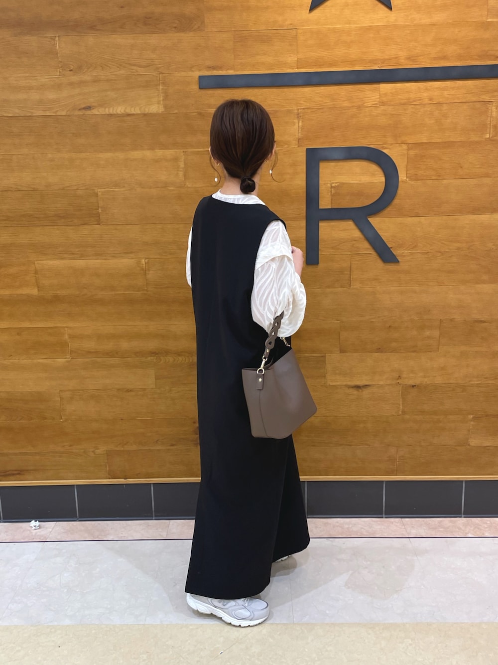 ブラック系のジャンパースカート、ホワイト系のシャツ/ブラウス、ブラウン系のバッグを着用したレディースの春コーディネートの1枚目の写真