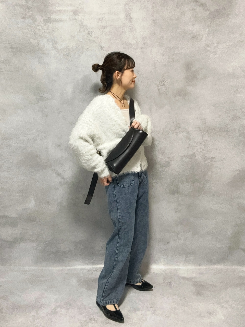 ホワイト系のニット/セーター、ブルー系のデニムパンツ、ブラック系のショルダーバッグを着用したレディースの秋コーディネートの1枚目の写真