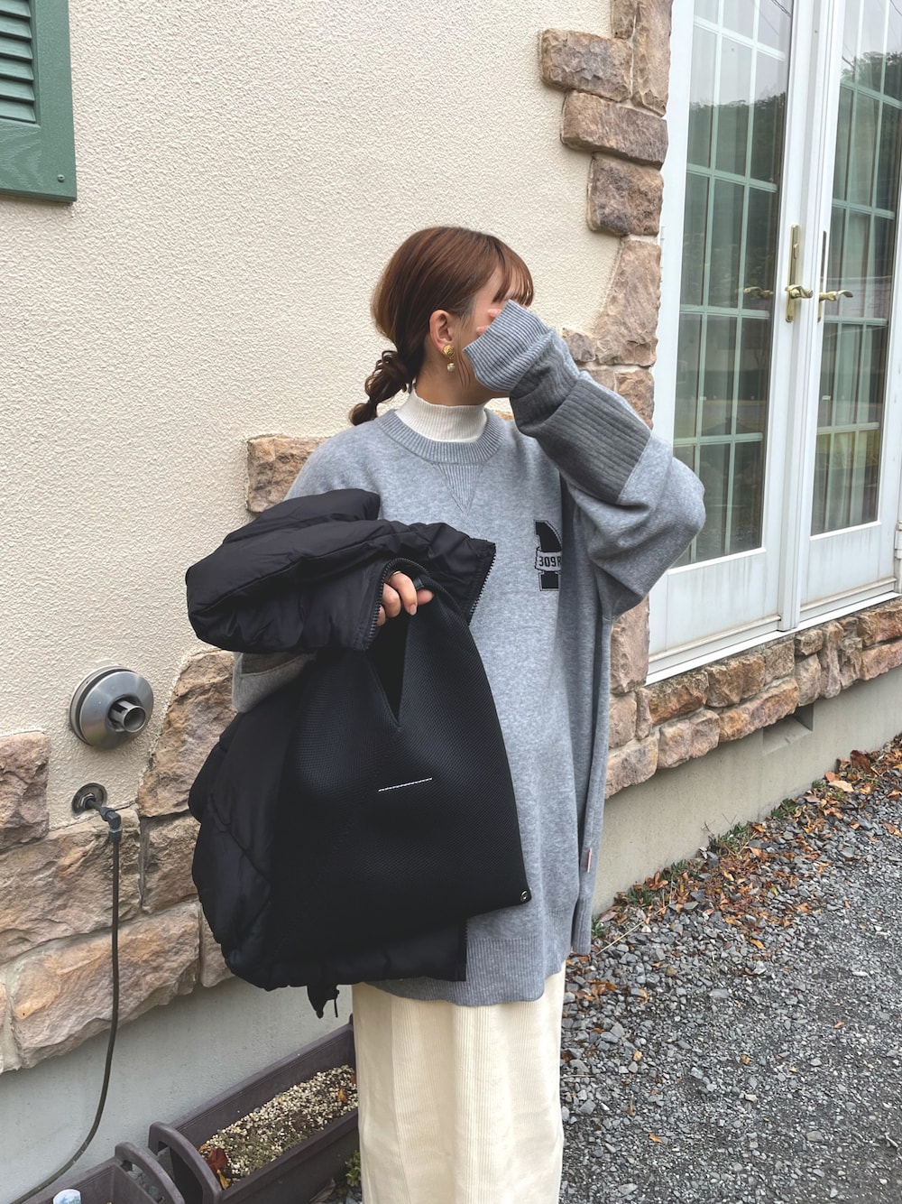 グレー系のニット/セーター、ホワイト系のスカート、ブラック系のベストを着用したレディースの秋コーディネートの1枚目の写真