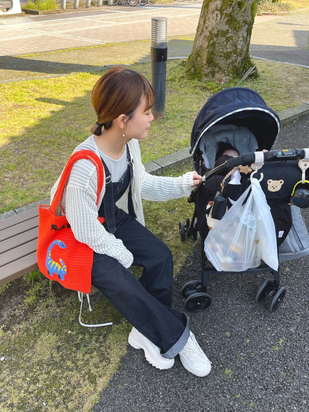 オレンジ系のトートバッグ、シルバー系のトップス、ホワイト系のカーディガン/ボレロを着用したレディースの春コーディネートの1枚目の写真