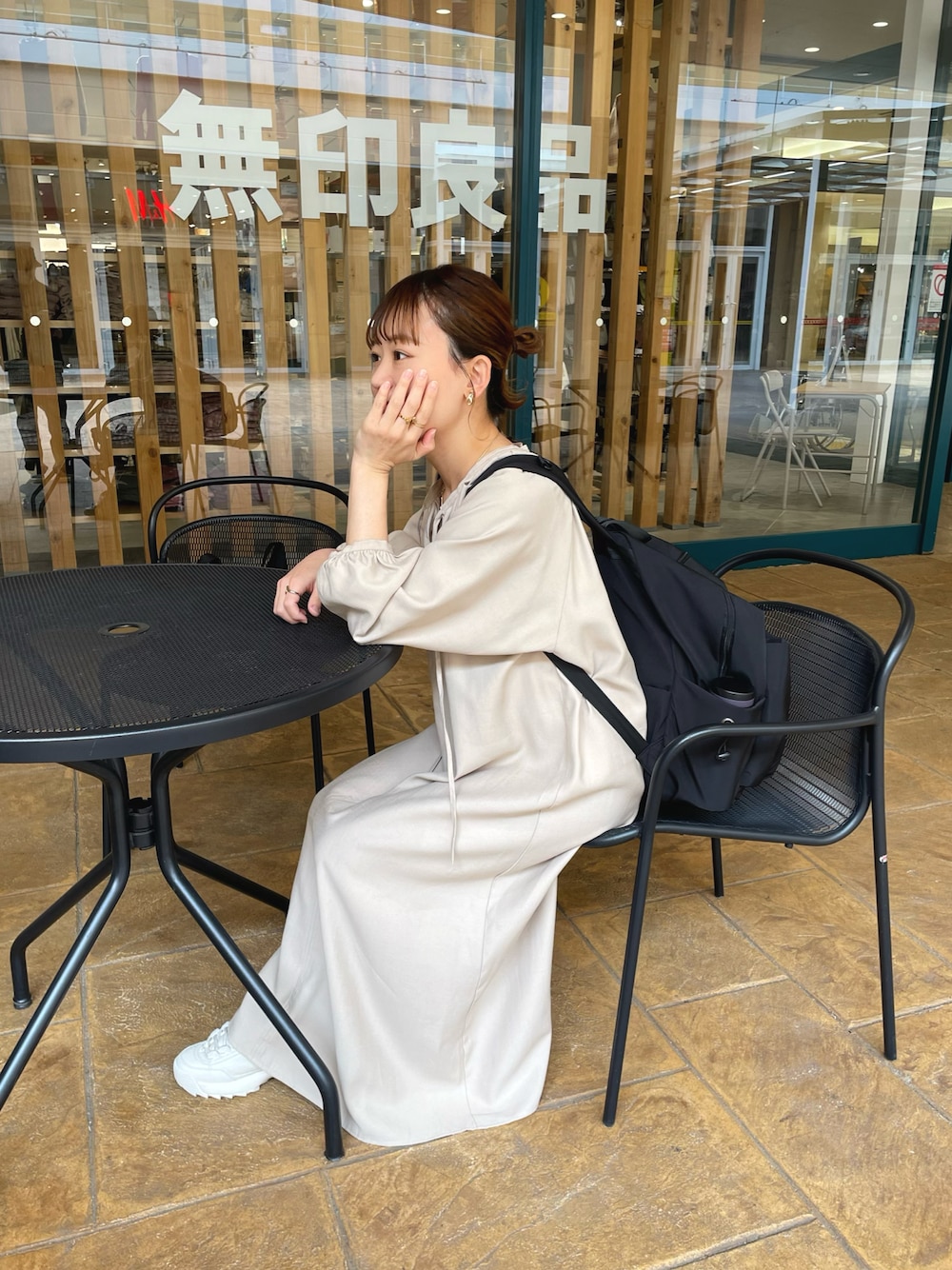 ベージュ系のワンピース、ブラック系のバックパック/リュック、ホワイト系のシューズを着用したレディースの春コーディネートの1枚目の写真