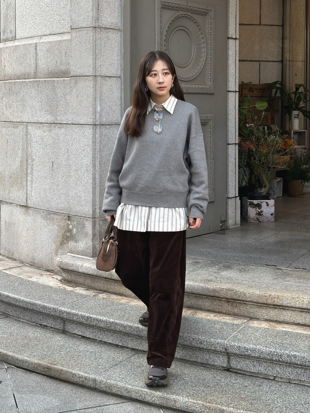 グレー系のニット/セーター、ホワイト系のシャツ/ブラウス、ブラウン系のその他パンツを着用したレディースの秋コーディネートの1枚目の写真