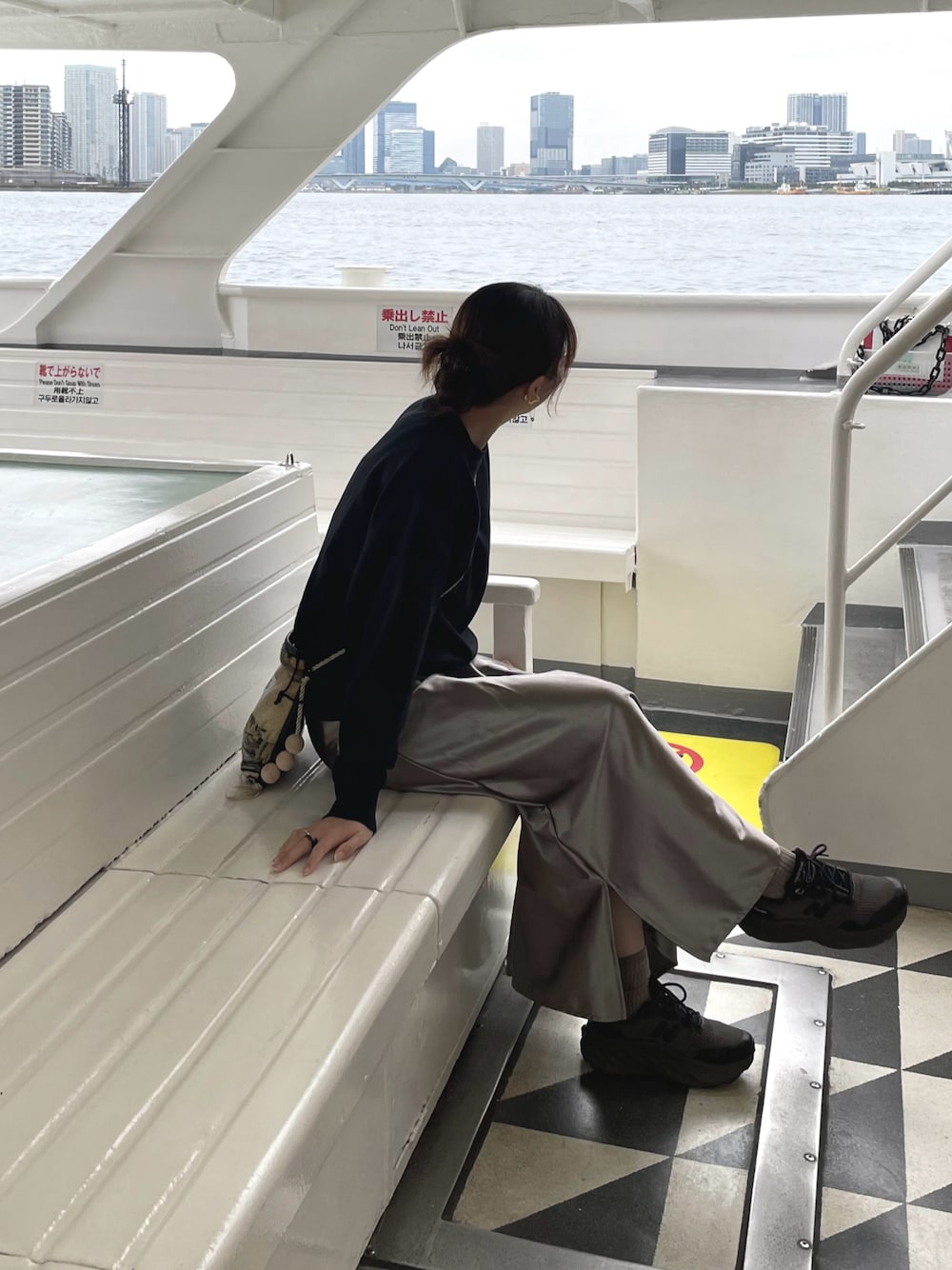 ブラック系のニット/セーター、ベージュ系のショルダーバッグ、グレー系のスニーカーを着用したレディースの秋コーディネートの1枚目の写真