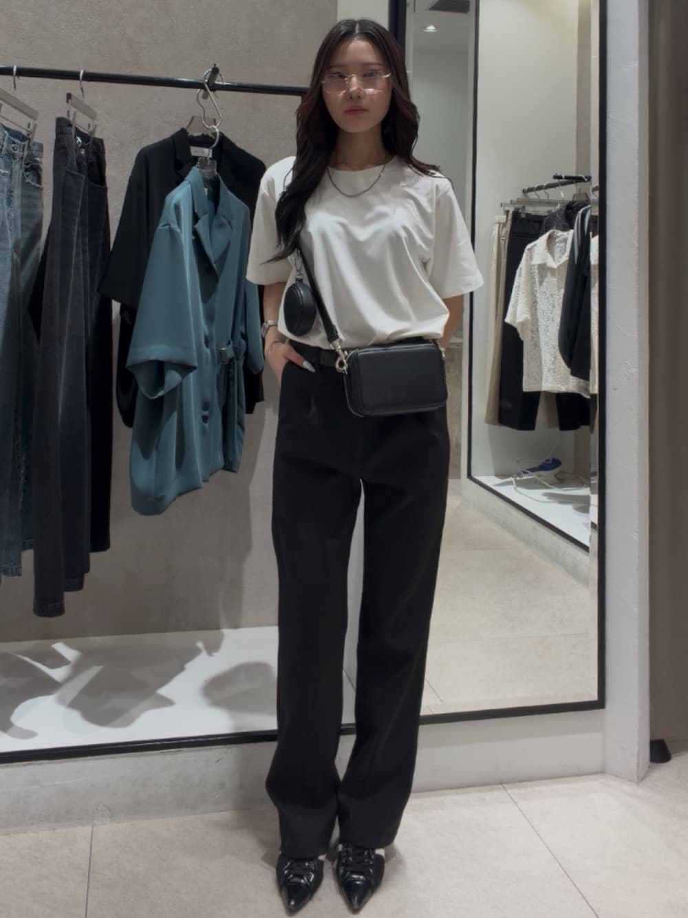 ブラック系のショルダーバッグ、ブラック系のスラックス、ホワイト系のTシャツ/カットソーを着用したレディースの春コーディネートの1枚目の写真