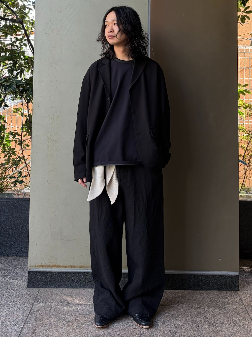 ブラック系のテーラードジャケット、ブラック系のスラックス、ブラック系のTシャツ/カットソーを着用したメンズの春コーディネートの1枚目の写真