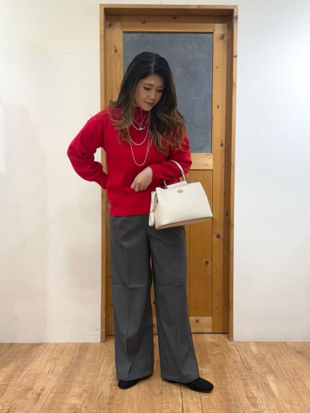 レッド系のニット/セーター、グレー系のその他パンツ、ブラック系のブーツを着用したレディースの秋コーディネートの1枚目の写真