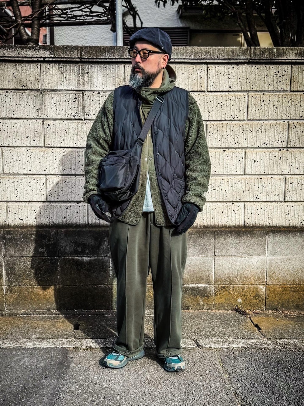 ブラック系のダウンベスト、グリーン系のミリタリージャケット、グリーン系のスウェットパンツを着用したメンズの冬コーディネートの1枚目の写真