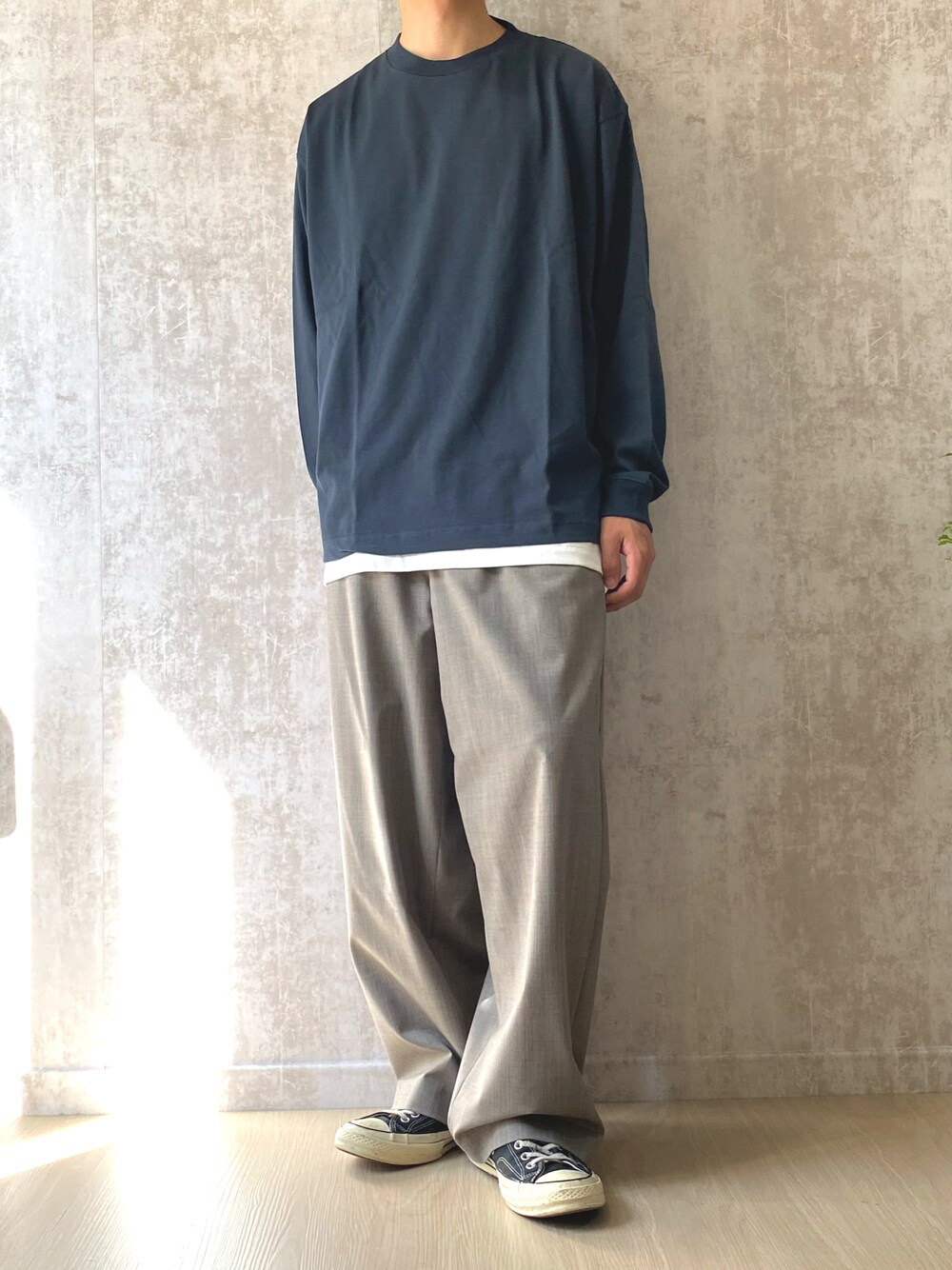 グリーン系のTシャツ/カットソー、ベージュ系のスラックス、ブラック系のスニーカーを着用したメンズの秋コーディネートの1枚目の写真