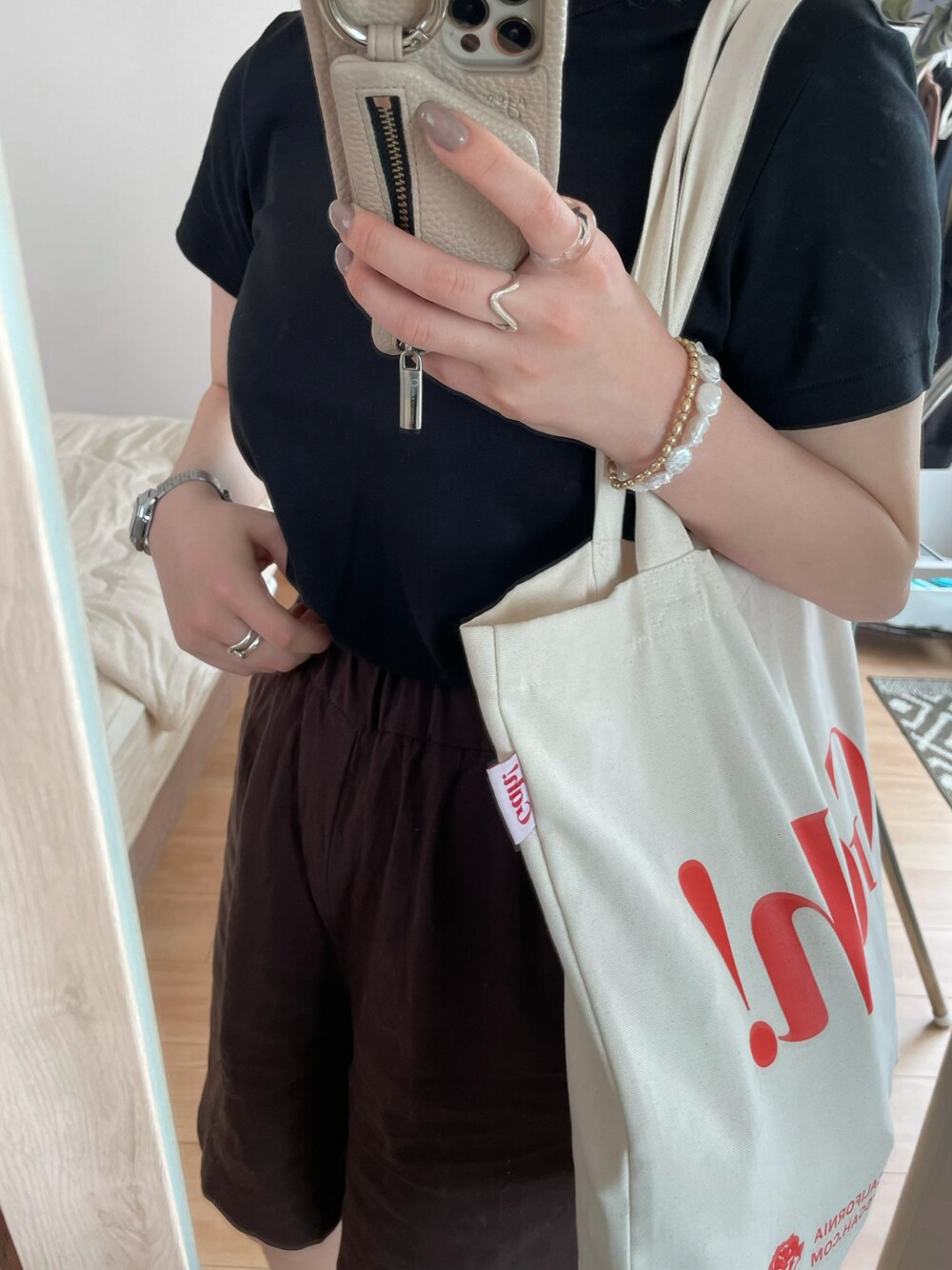 ベージュ系のトートバッグ、ブラック系のTシャツ/カットソーを着用したレディースの夏コーディネートの1枚目の写真