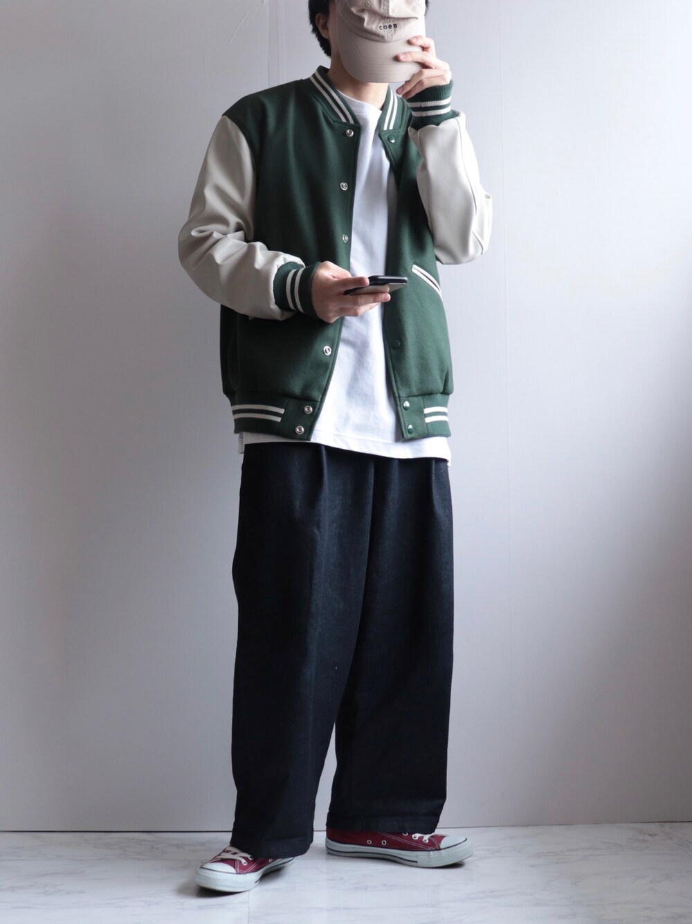 グリーン系のスタジャン、ブルー系のデニムパンツ、レッド系のスニーカーを着用したメンズの冬コーディネートの1枚目の写真