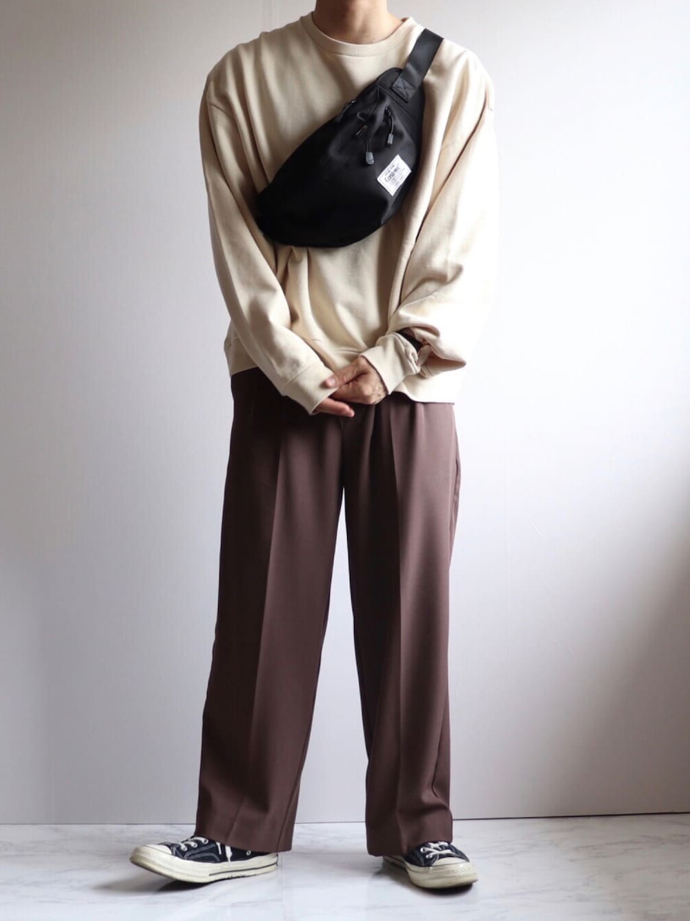 ベージュ系のスウェット、ブラック系のボディバッグ/ウエストポーチ、ブラウン系のスラックスを着用したメンズの秋コーディネートの1枚目の写真