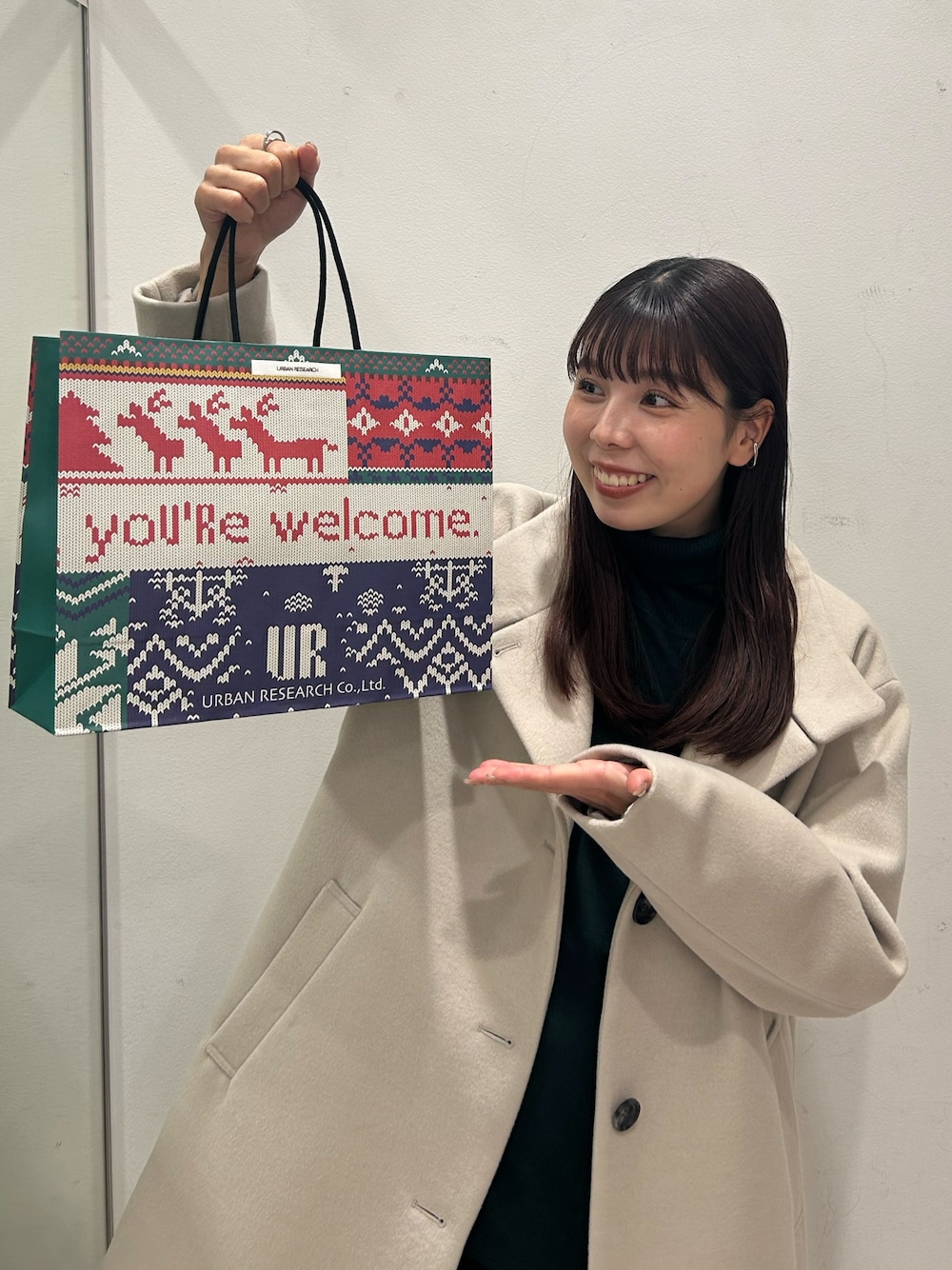ベージュ系のその他アウター、グリーン系のニット/セーター、レッド系のストール/ショールを着用したレディースの冬コーディネートの1枚目の写真