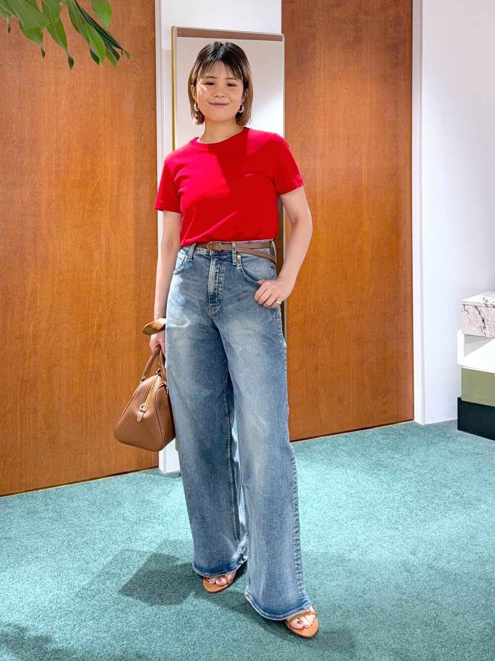 ブルー系のデニムパンツ、レッド系のTシャツ/カットソー、ブラウン系のボストンバッグを着用したレディースの春コーディネートの1枚目の写真