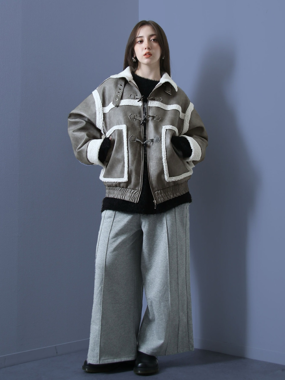 グレー系のムートンコート、ブラック系のニット/セーター、グレー系のスウェットパンツを着用したレディースの冬コーディネートの1枚目の写真