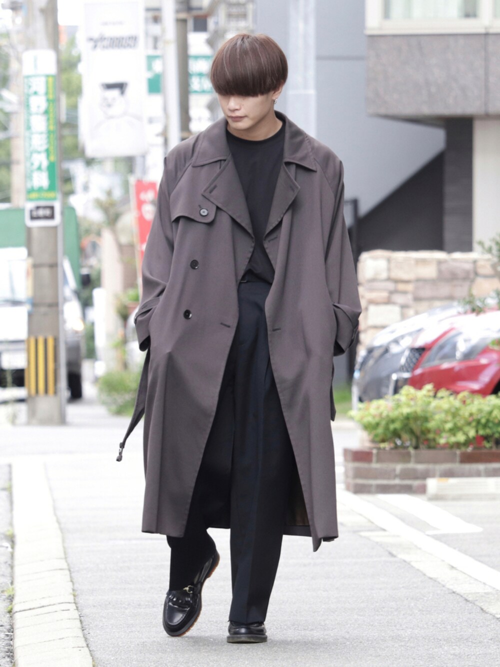 グレー系のTシャツ/カットソー、グレー系のトレンチコート、ブラック系のスラックスを着用したメンズの秋コーディネートの1枚目の写真