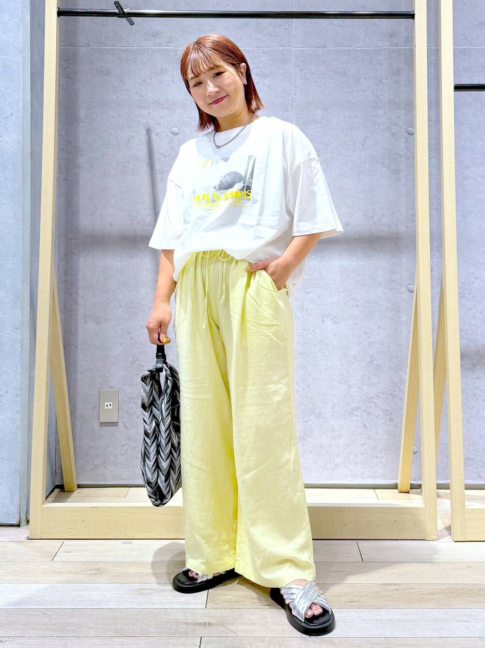 ブラック系のハンドバッグ、イエロー系のその他パンツ、シルバー系のサンダルを着用したレディースの夏コーディネートの1枚目の写真