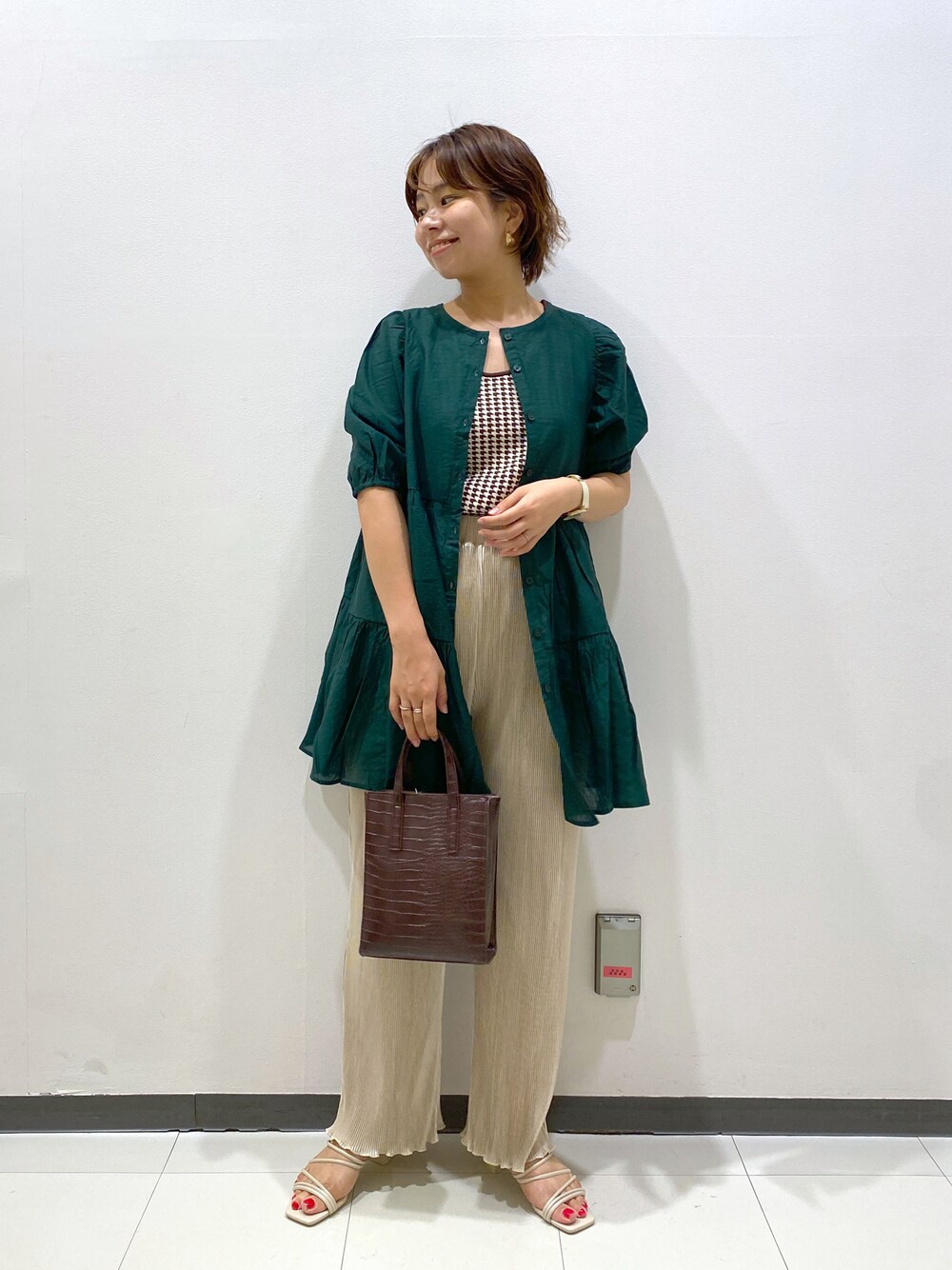 ブラウン系のショルダーバッグ、ホワイト系のサンダル、グリーン系のシャツ/ブラウスを着用したレディースの夏コーディネートの1枚目の写真