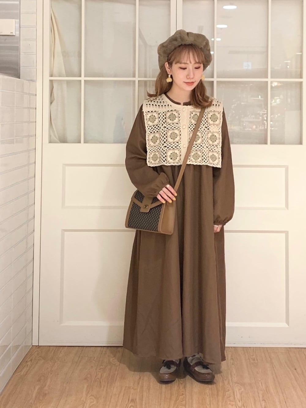 ブラウン系のワンピース、ホワイト系のベスト、ブラウン系のショルダーバッグを着用したレディースの秋コーディネートの1枚目の写真