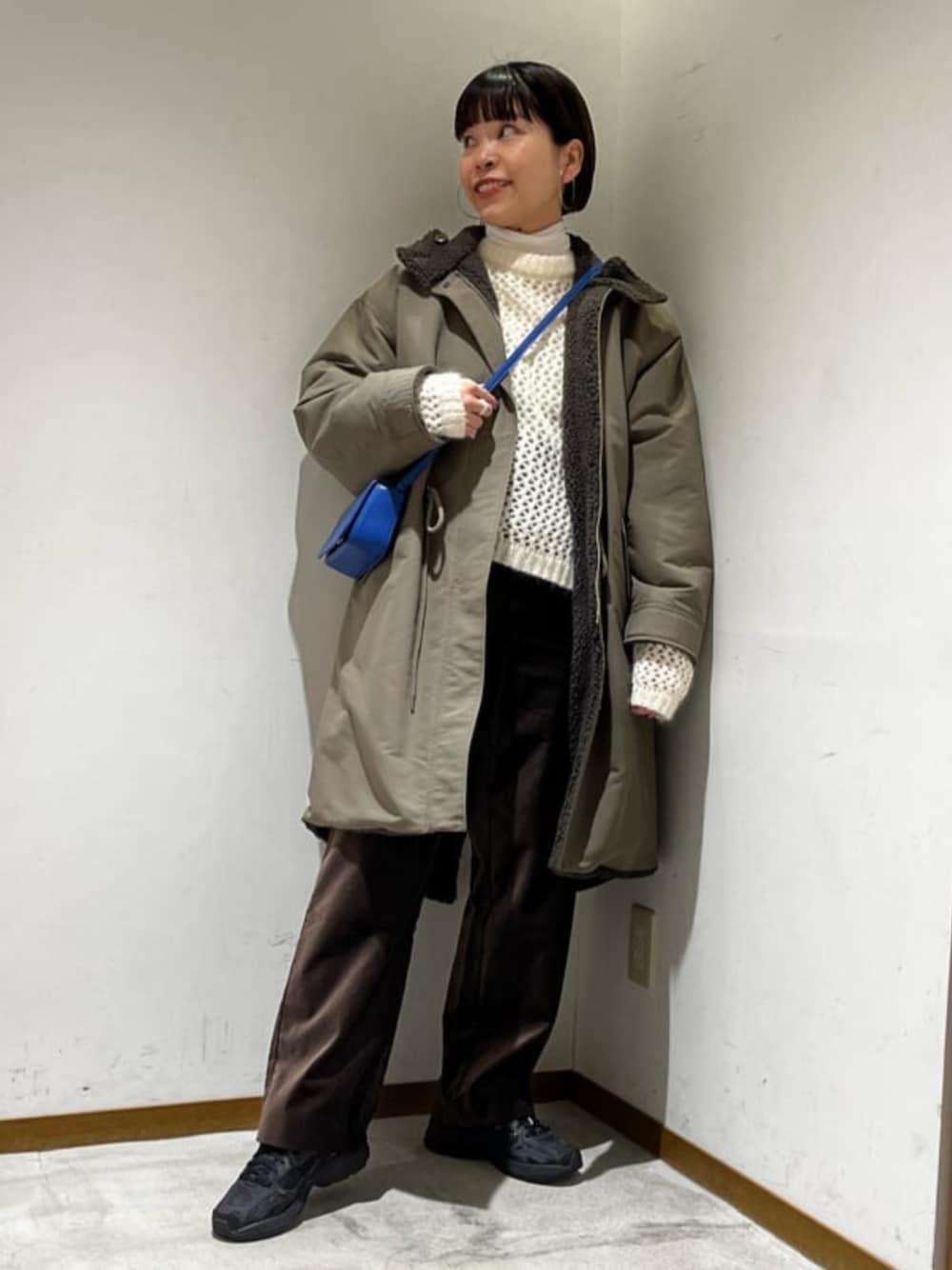 ブルー系のショルダーバッグ、ホワイト系のニット/セーター、ホワイト系のTシャツ/カットソーを着用したレディースの冬コーディネートの1枚目の写真