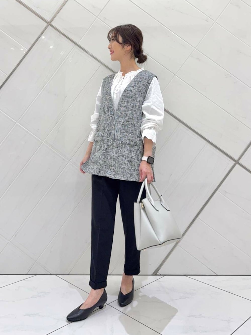 ホワイト系のショルダーバッグ、ホワイト系のシャツ/ブラウス、ブラック系のベストを着用したレディースの冬コーディネートの1枚目の写真