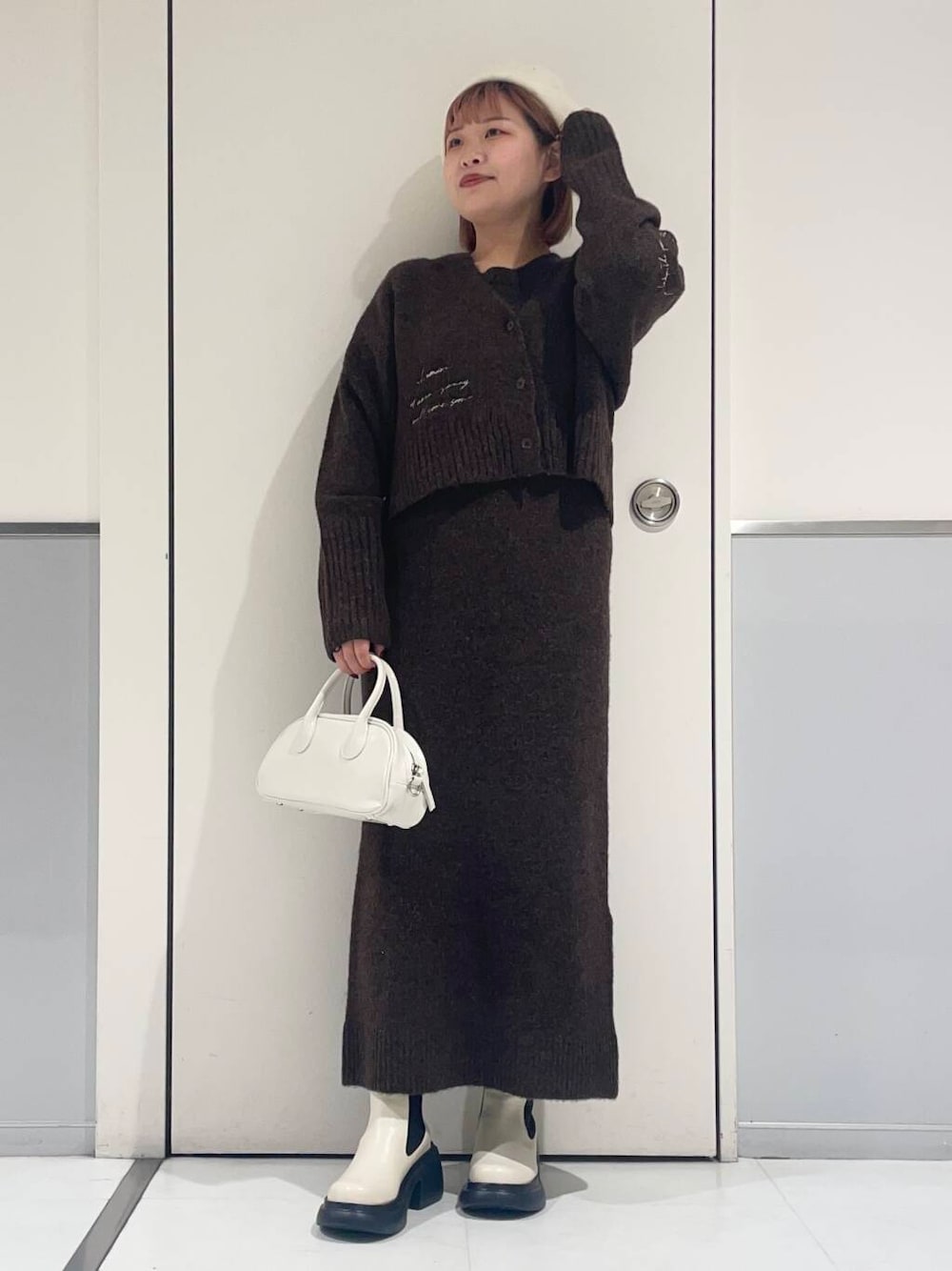 ホワイト系のブーツ、ホワイト系のボストンバッグ、ブラウン系のワンピースを着用したレディースの冬コーディネートの1枚目の写真