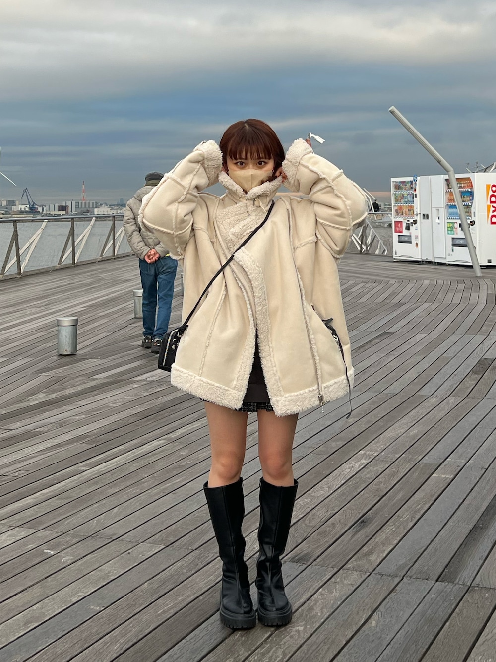 ブラック系のブーツ、ホワイト系のムートンコート、ブラック系のスカートを着用したレディースの冬コーディネートの1枚目の写真