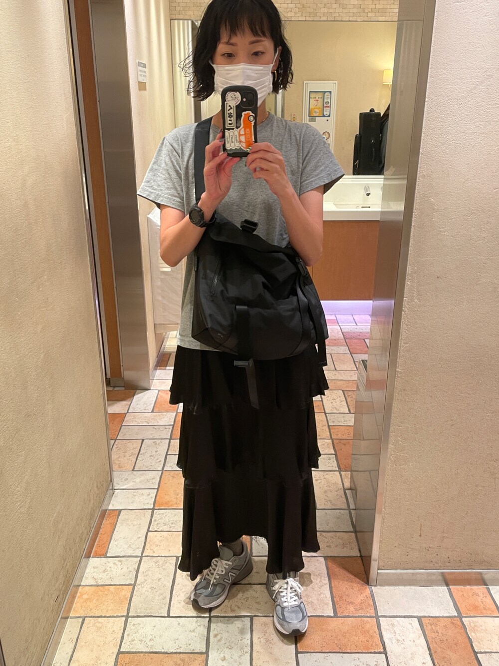 ブラック系のスカート、グレー系のTシャツ/カットソー、グレー系のスニーカーを着用したレディースの秋コーディネートの1枚目の写真