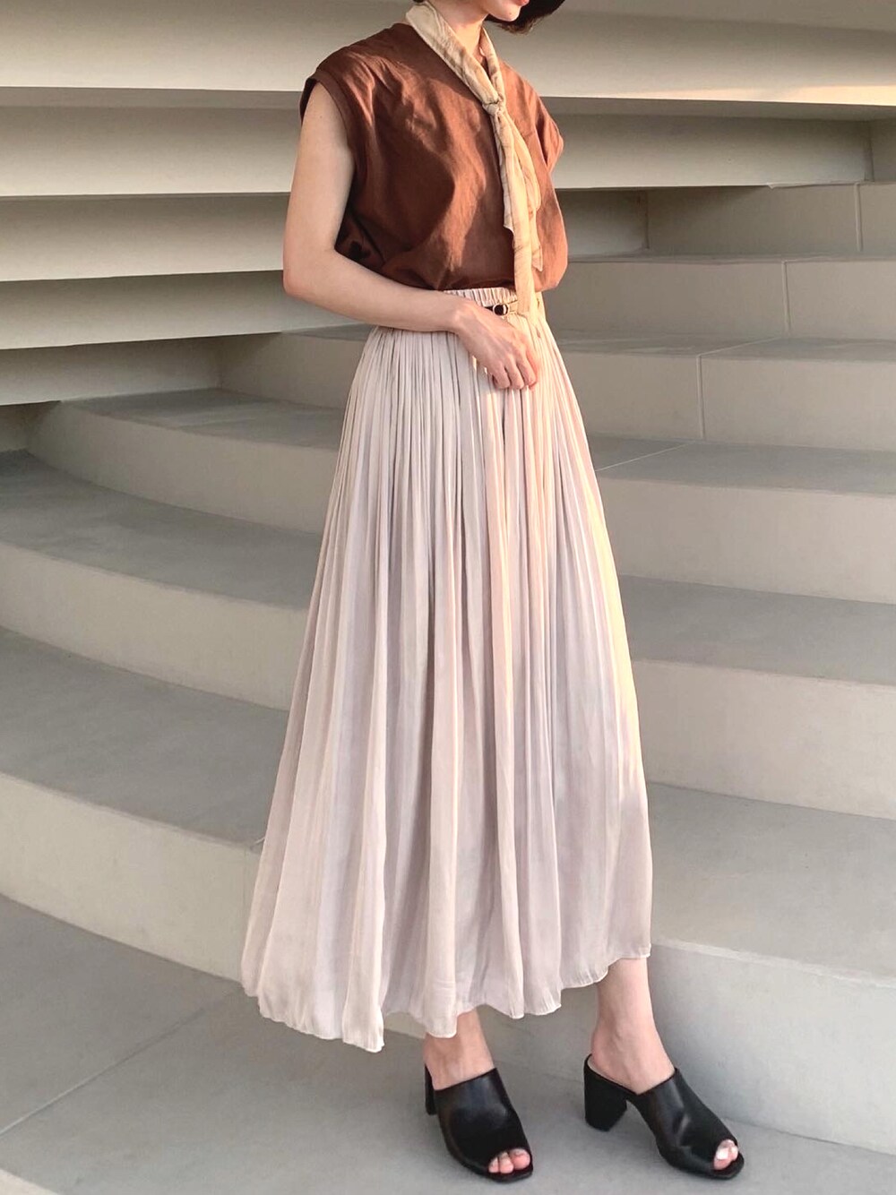 ブラウン系のTシャツ/カットソー、ホワイト系のスカート、ブラック系のサンダルを着用したレディースの夏コーディネートの1枚目の写真