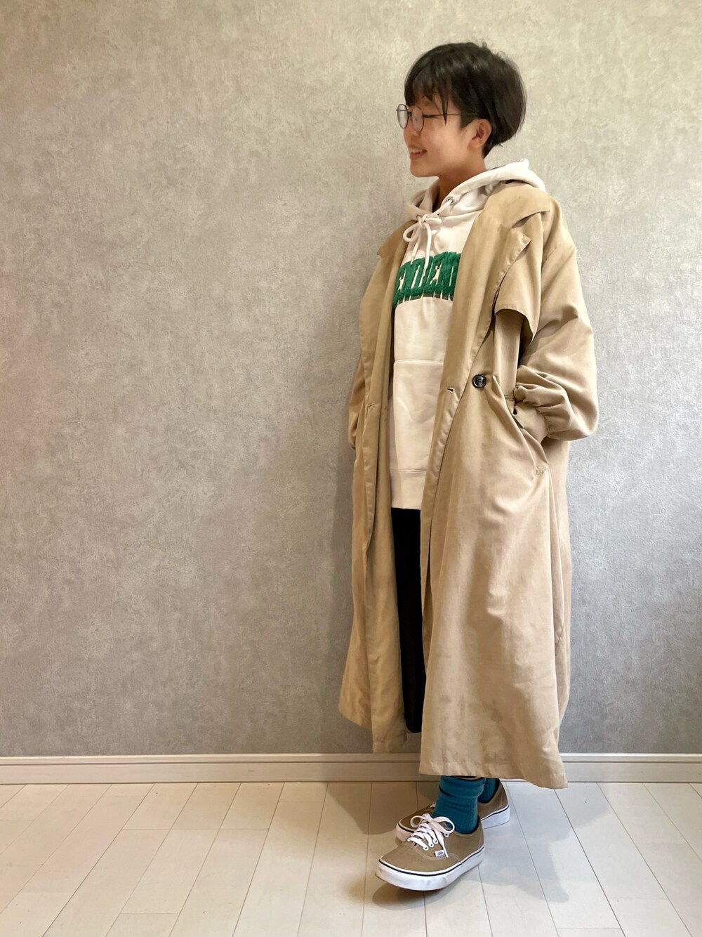 ベージュ系のトレンチコート、ホワイト系のパーカー、ブラック系のスカートを着用したキッズの冬コーディネートの1枚目の写真