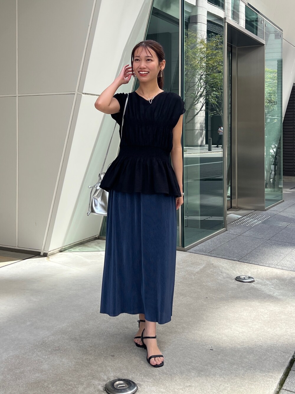 ブラック系のシャツ/ブラウス、ブルー系のスカート、シルバー系のトートバッグを着用したレディースの春コーディネートの1枚目の写真