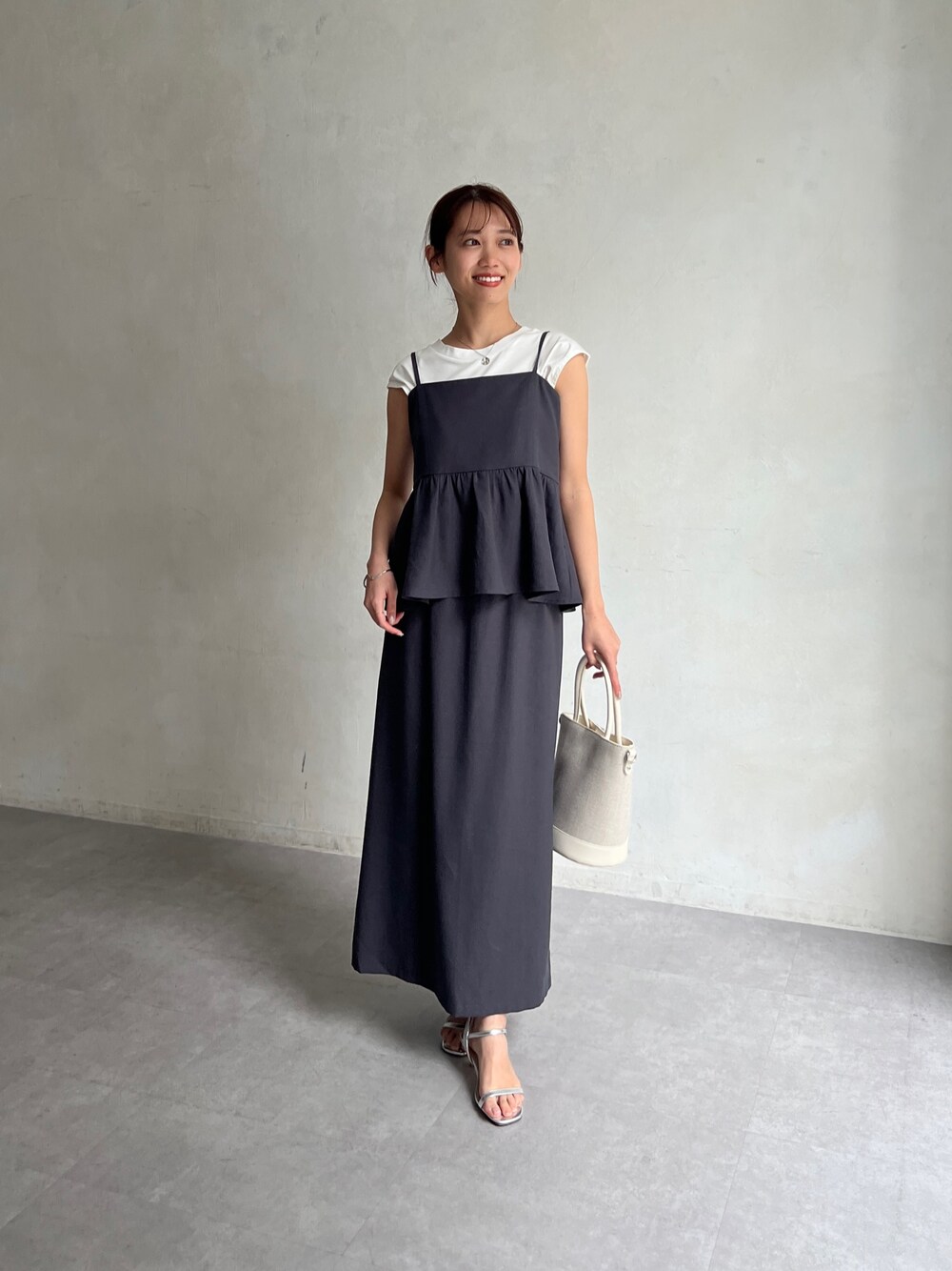 グレー系のワンピース、ホワイト系のトートバッグ、シルバー系のサンダルを着用したレディースの春コーディネートの1枚目の写真