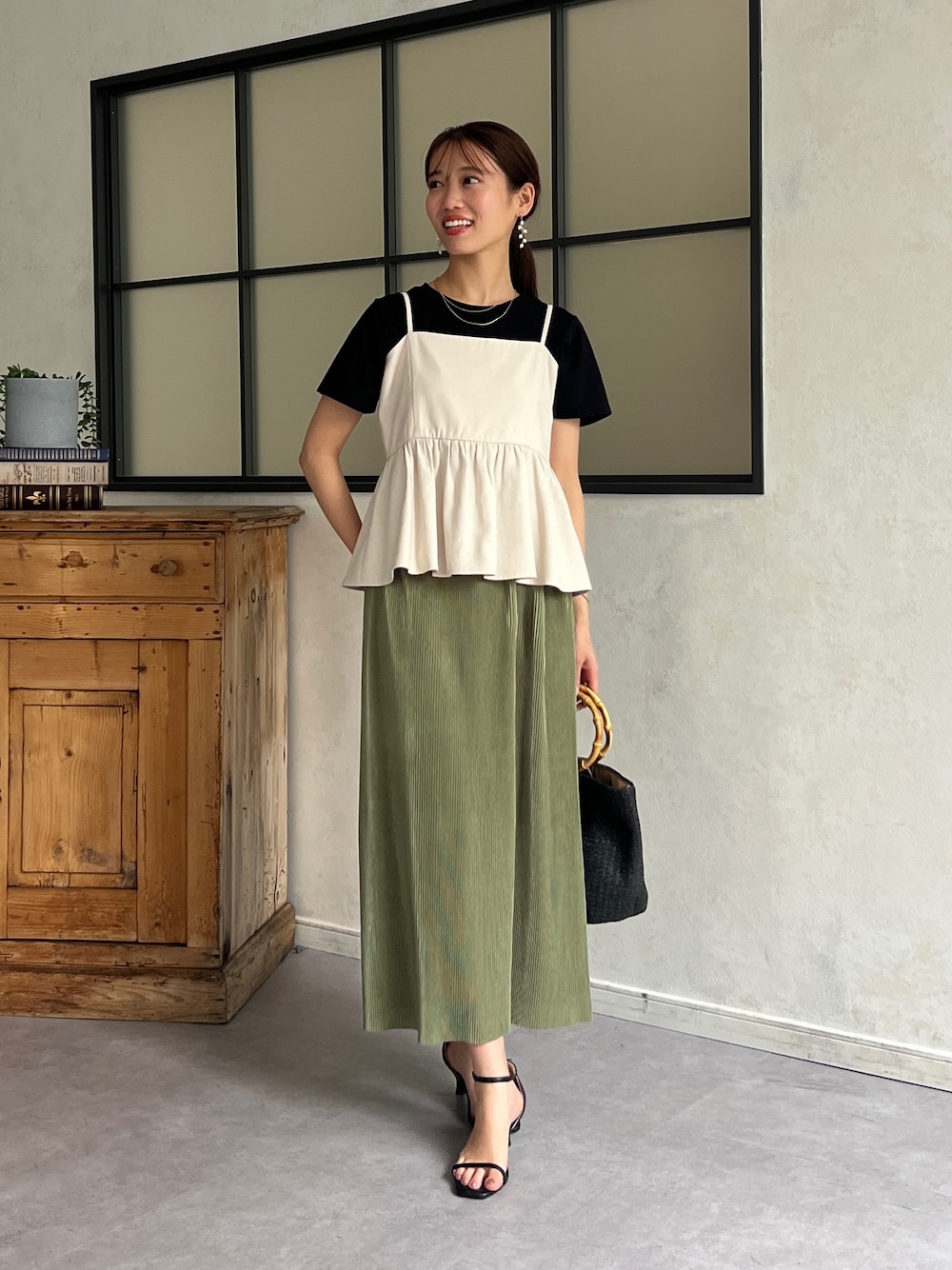 ホワイト系のワンピース、ブラック系のTシャツ/カットソー、グリーン系のスカートを着用したレディースの春コーディネートの1枚目の写真