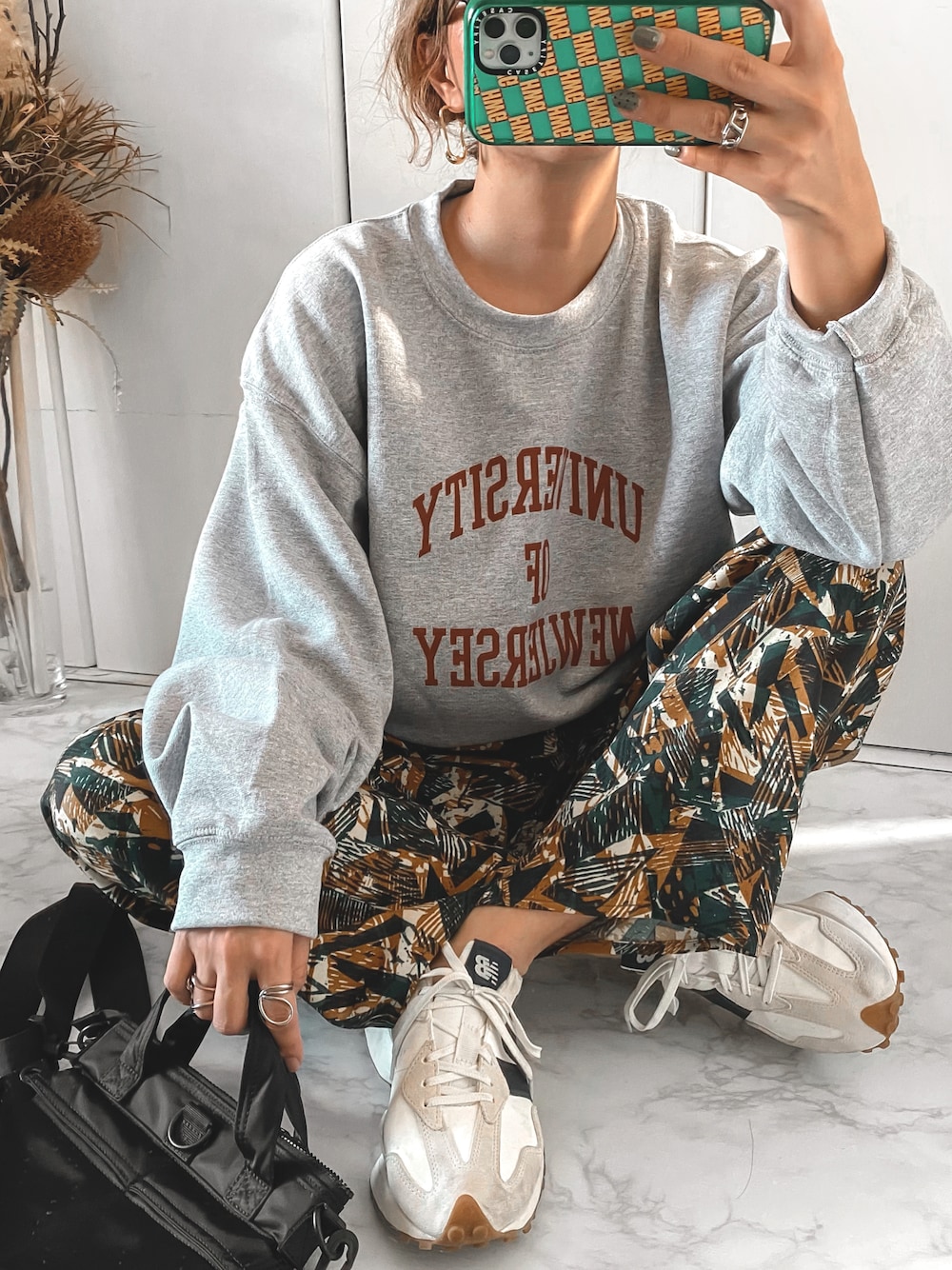 グレー系のスウェット、グリーン系のその他パンツ、ホワイト系のスニーカーを着用したレディースの秋コーディネートの1枚目の写真