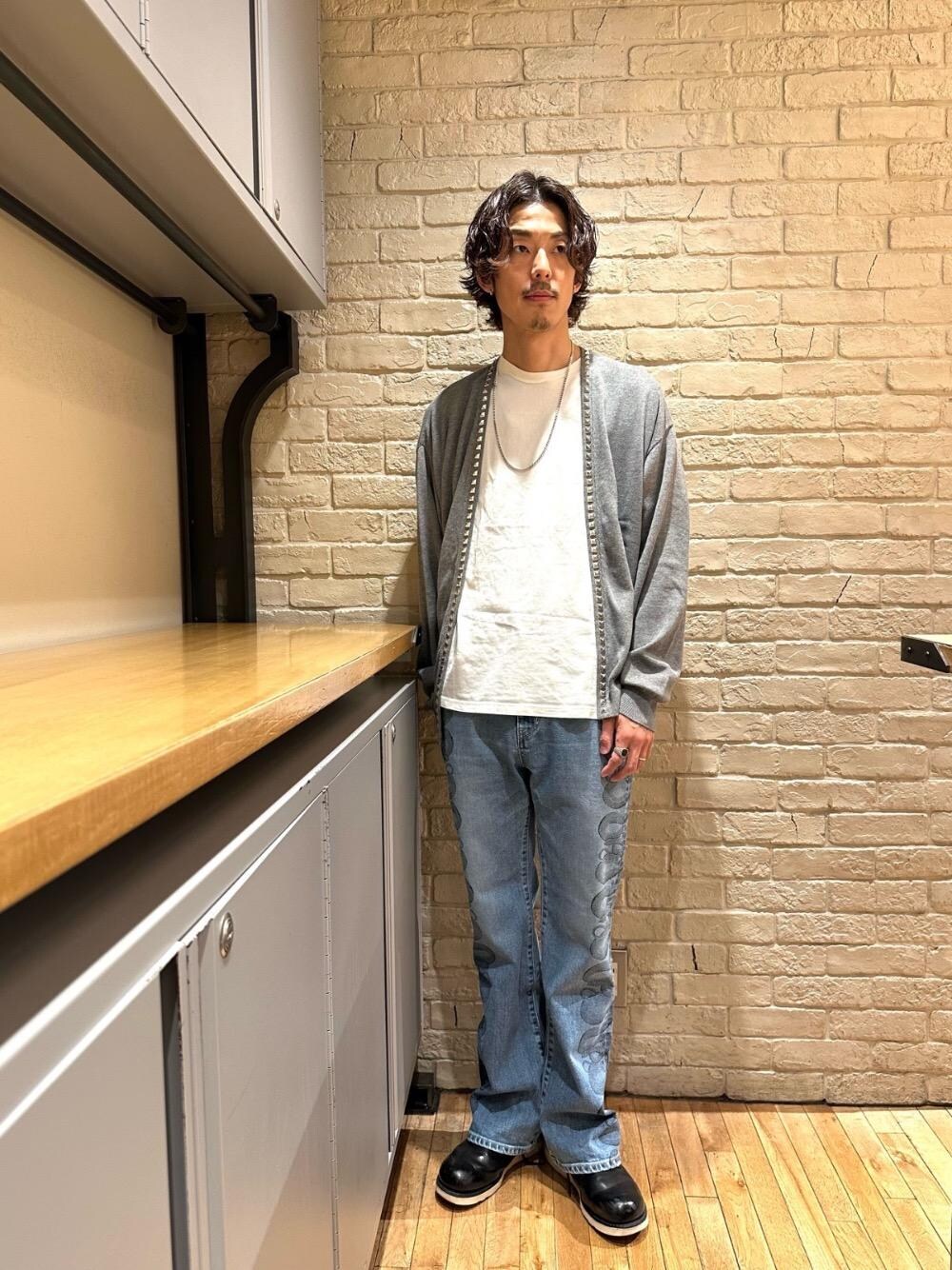 ブルー系のデニムパンツ、ホワイト系のTシャツ/カットソー、グレー系のニット/セーターを着用したメンズの春コーディネートの1枚目の写真