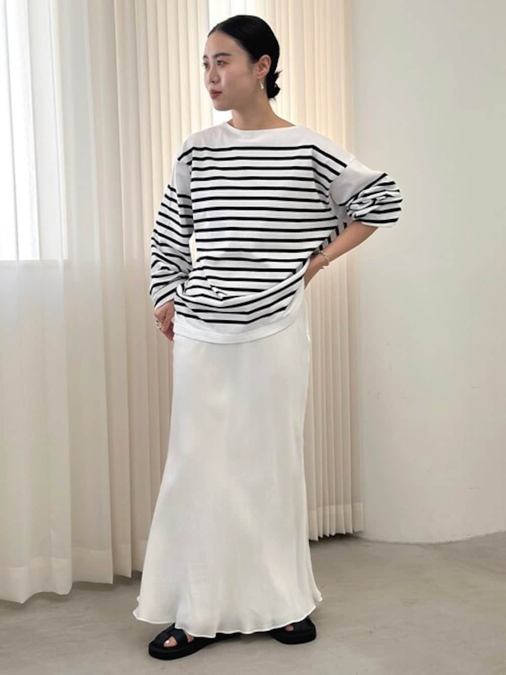 ホワイト系のTシャツ/カットソー、ホワイト系のスカート、ブラック系のサンダルを着用したレディースの春コーディネートの1枚目の写真