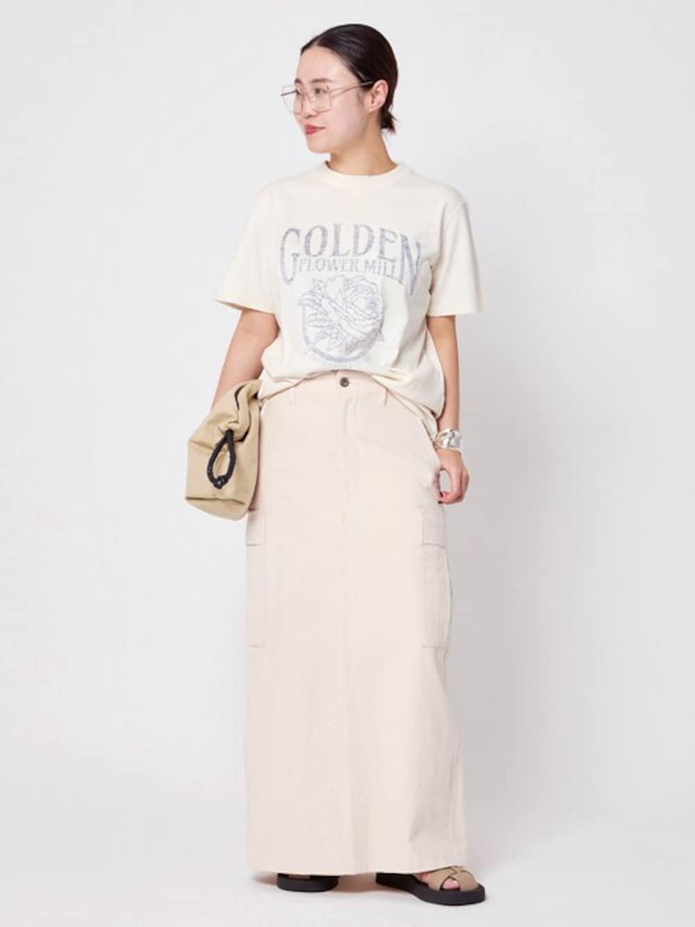 ホワイト系のスカート、ベージュ系のサンダルを着用したレディースの春コーディネートの1枚目の写真