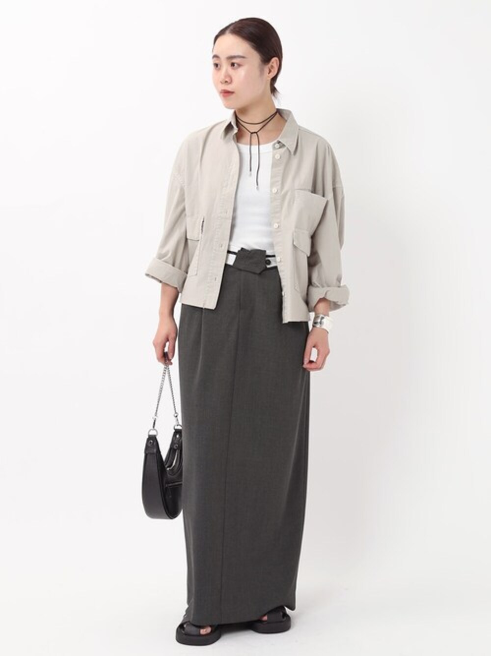 グレー系のスカート、ホワイト系のシャツ/ブラウス、ブラック系のサンダルを着用したレディースの春コーディネートの1枚目の写真