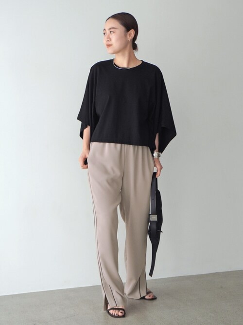 ブラック系のTシャツ/カットソー、ベージュ系のスラックス、ブラック系のショルダーバッグを着用したレディースの春コーディネートの1枚目の写真