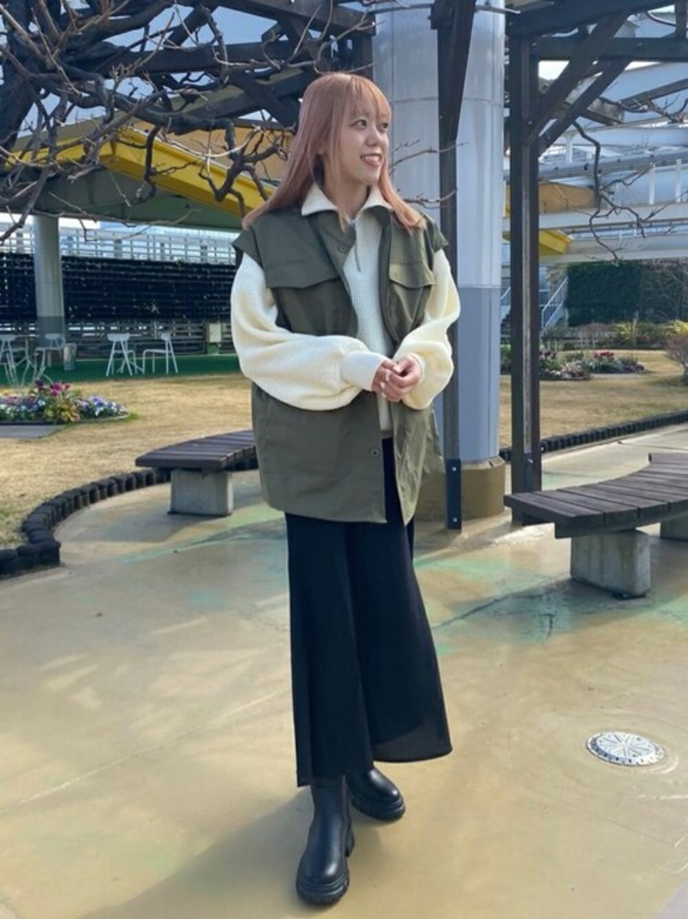 グリーン系のベスト、ホワイト系のニット/セーター、ブラック系のワンピースを着用したレディースの冬コーディネートの1枚目の写真