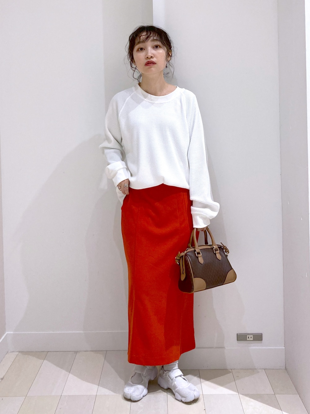 ブラウン系のボストンバッグ、ホワイト系のTシャツ/カットソー、レッド系のスカートを着用したレディースの春コーディネートの1枚目の写真