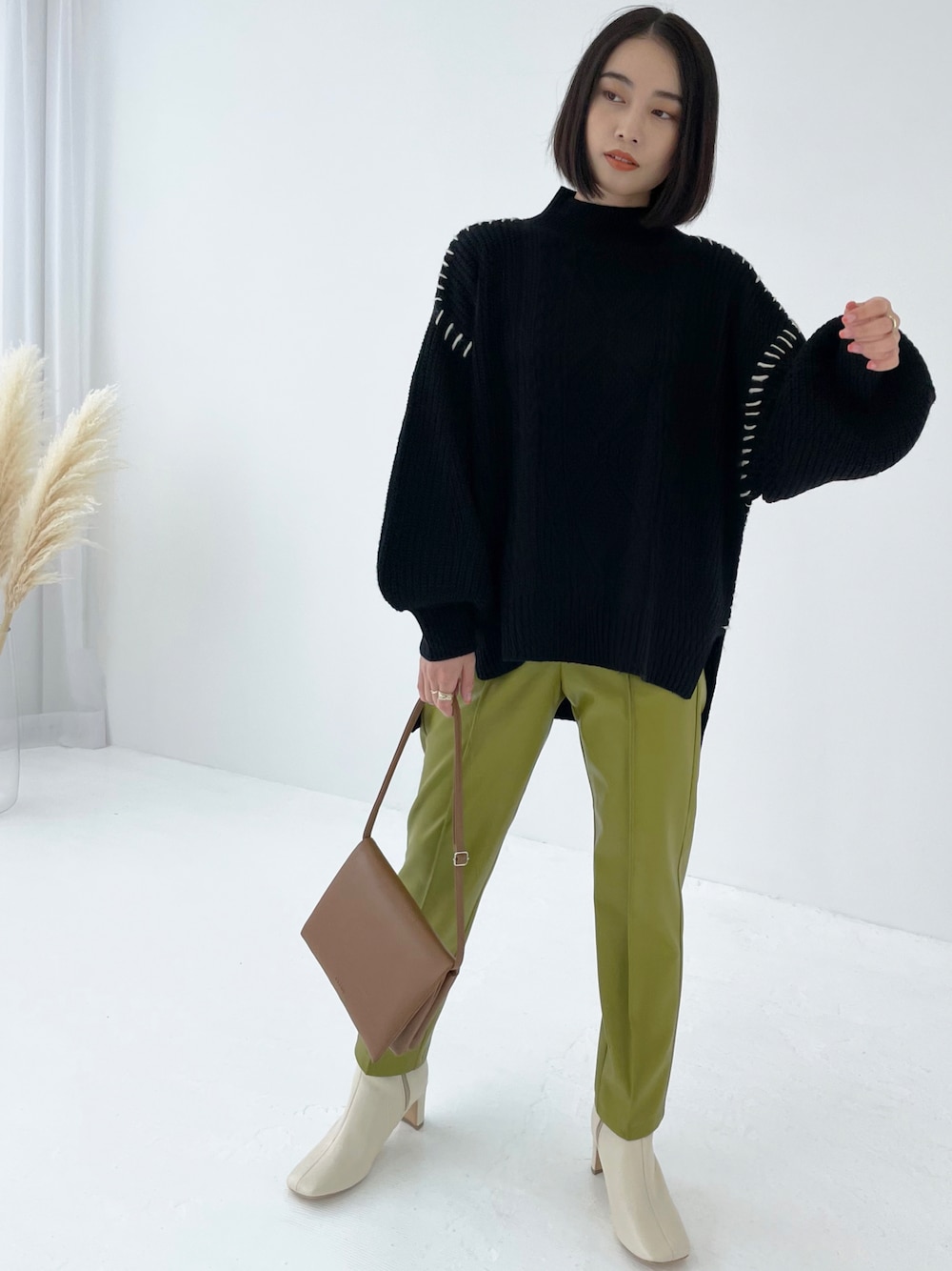 ブラック系のニット/セーター、グリーン系のスラックスを着用したレディースの秋コーディネートの1枚目の写真
