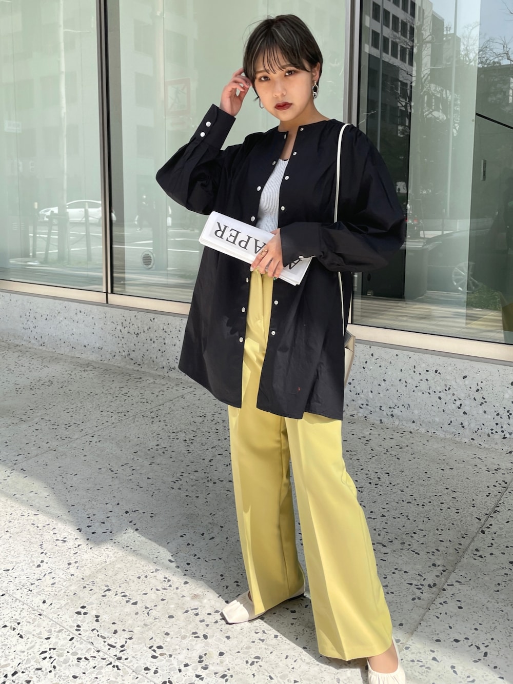 ブラック系のシャツ/ブラウス、イエロー系のスラックス、ホワイト系のパンプスを着用したレディースの春コーディネートの1枚目の写真